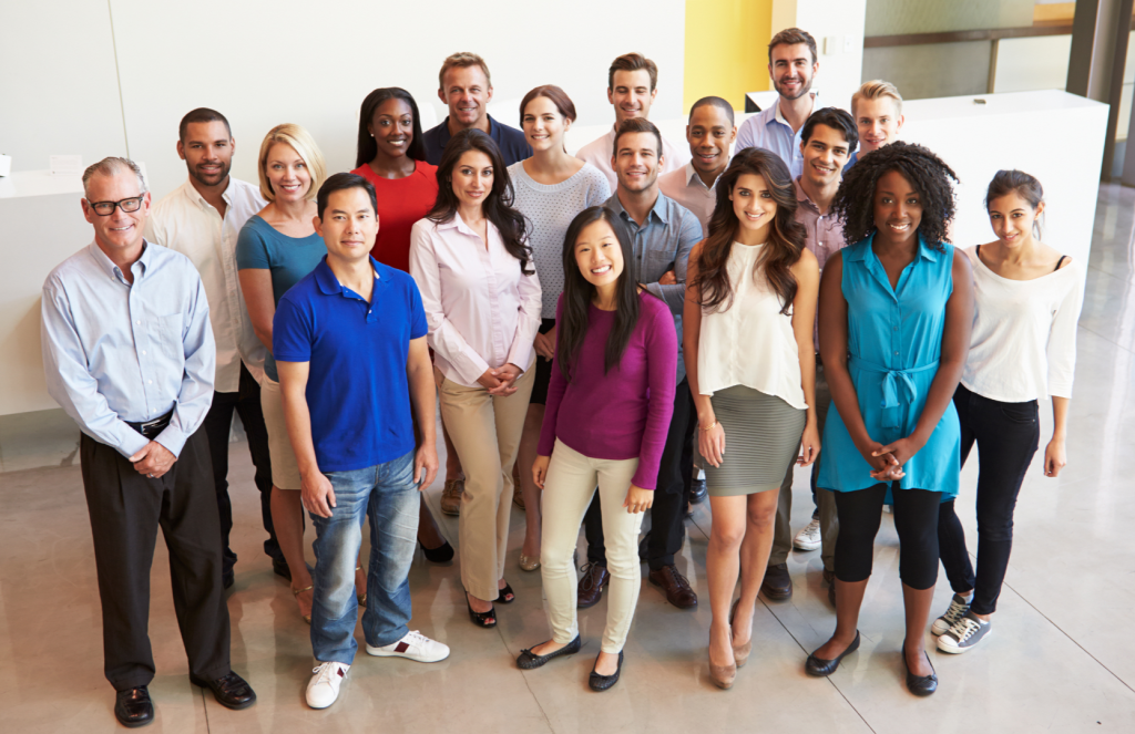 happy diverse office employees standing in a group posing for a picture.png
